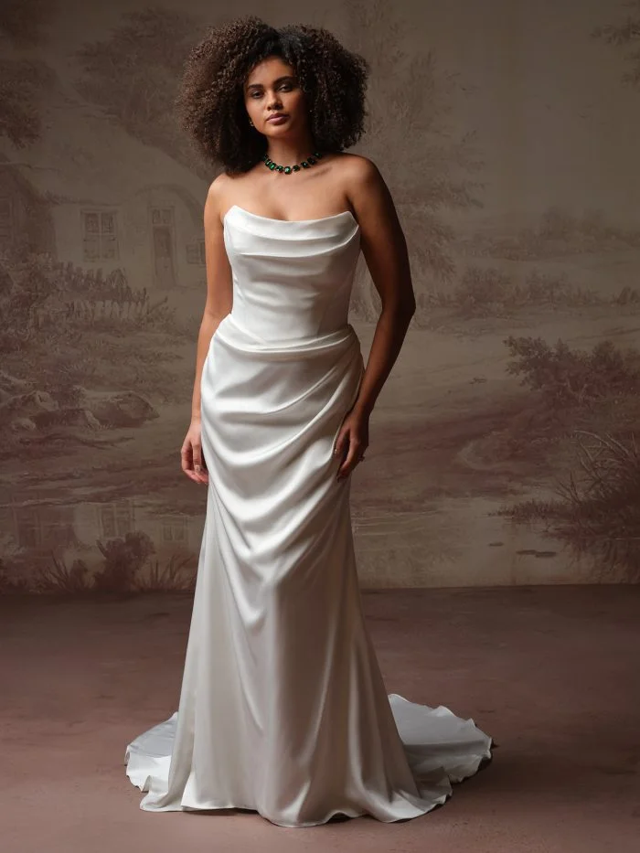 Bride wearing Prestyn by Maggie Sottero, a modern sheath wedding gown with a sculpted neckline and smooth crepe fabric.