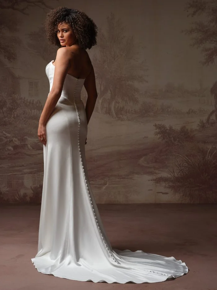 Back view of Prestyn by Maggie Sottero showcasing covered buttons trailing to the hem of a sleek crepe wedding dress.
