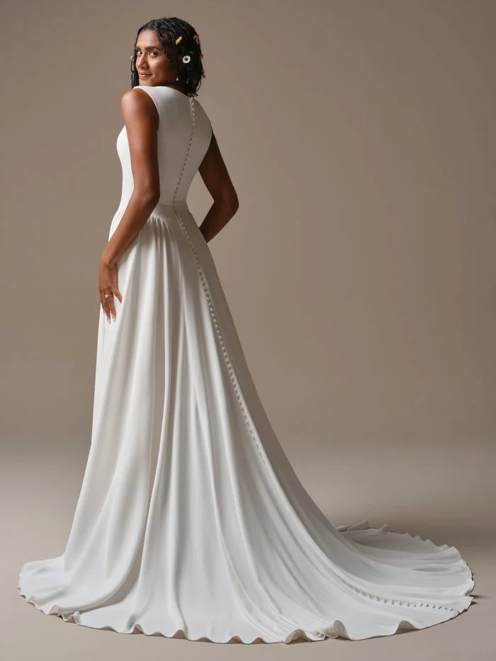 Back view of Shay by Rebecca Ingram showcasing covered buttons trailing to the hem of a classic crepe wedding dress.