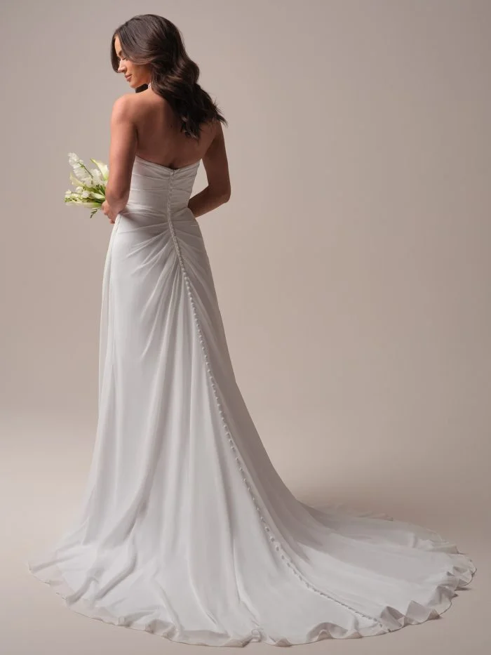 Back view of Francesca by Rebecca Ingram showcasing covered buttons trailing to the hem of a flowing chiffon wedding dress.