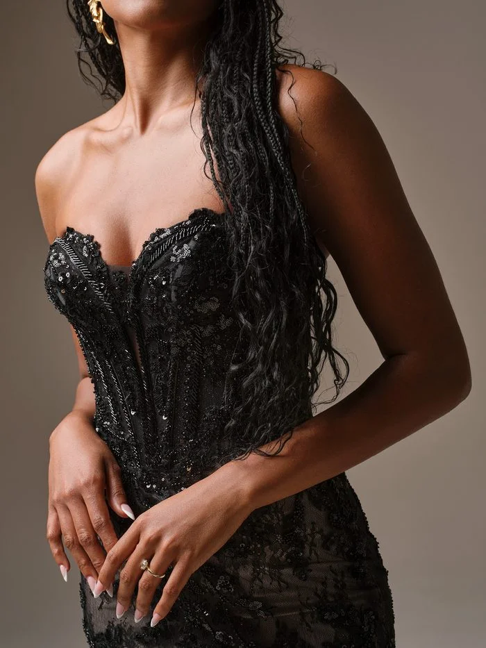 Close-up detail of Benjie by Maggie Sottero in Black, showcasing the structured corset bodice with a sweetheart neckline, illusion plunge inset, and allover black beadwork, sequins, and lace appliqués. The image highlights the gown’s dimensional texture, shimmering embellishments, and couture-inspired construction for a bold monochromatic bridal look.