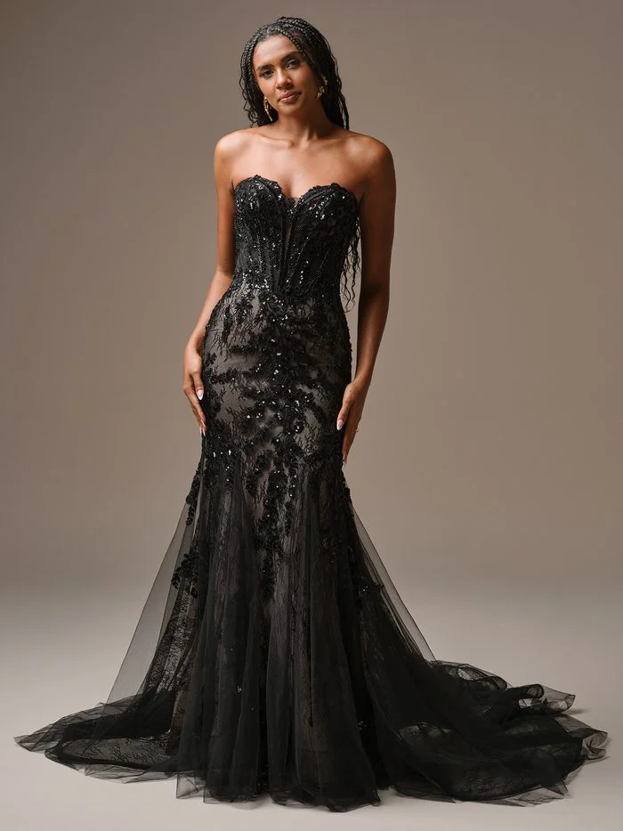 Serafina by Maggie Sottero in Black, a dramatic ballgown wedding dress featuring a strapless sweetheart neckline, a corset-inspired bodice with exposed boning, and matte black floral lace appliqués. The voluminous satin skirt creates a regal silhouette, while a coordinating black veil with embroidered floral accents frames the gown. Photographed in a studio setting, the design blends romantic detailing with gothic-inspired elegance.