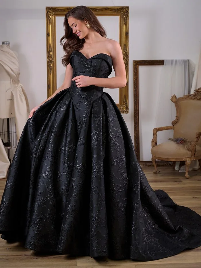 Back view of Aberdeen by Sottero and Midgley in Black, showcasing the strapless corset bodice, low back, and a row of covered buttons extending through the skirt and into the cathedral-length train. The black floral jacquard fabric features a subtle textured pattern and soft sheen, emphasizing the gown’s dramatic volume and sophisticated architectural silhouette.