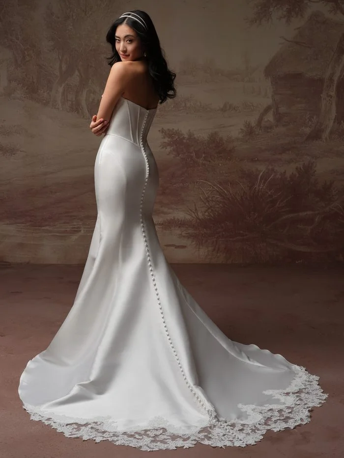 Back view of the Rebecca Ingram Zorina Lane fit-and-flare wedding gown with covered buttons, lace-trimmed train, and a figure-hugging silhouette.