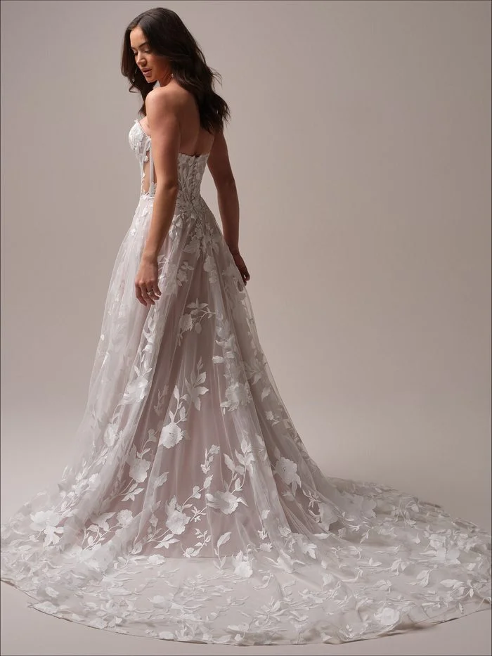 Back view of the Maggie Sottero Natalie A-line wedding gown showcasing oversized floral lace, a sheer corset-inspired bodice, and a sweeping train