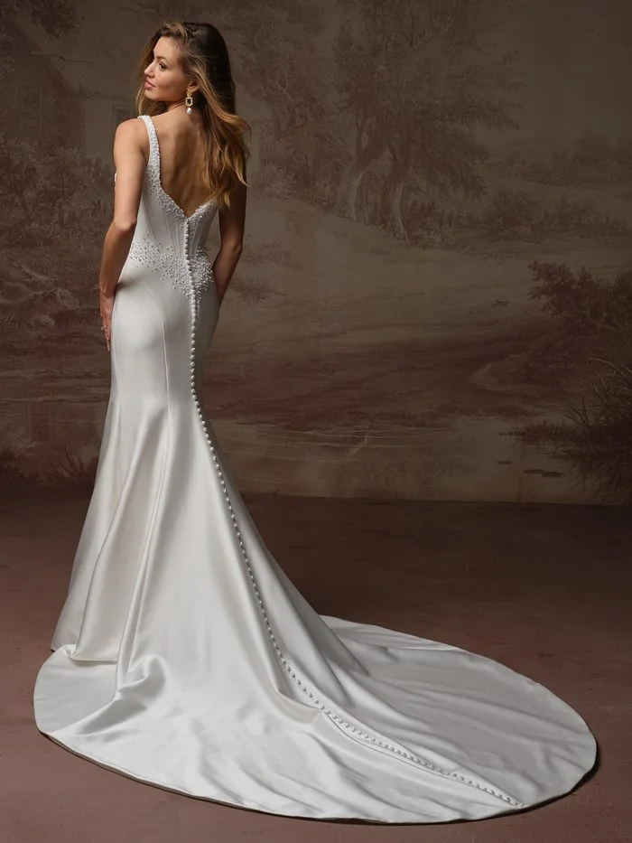 Back view of the Melissa Marie Royale by Maggie Sottero wedding gown featuring a sleek satin fit-and-flare silhouette with a low V-back neckline. Pearl embellishments accent the shoulder straps and waistline, while covered buttons cascade from the back bodice through the length of the elegant train. The fitted silhouette flares softly below the hips, creating a clean and sophisticated finish.