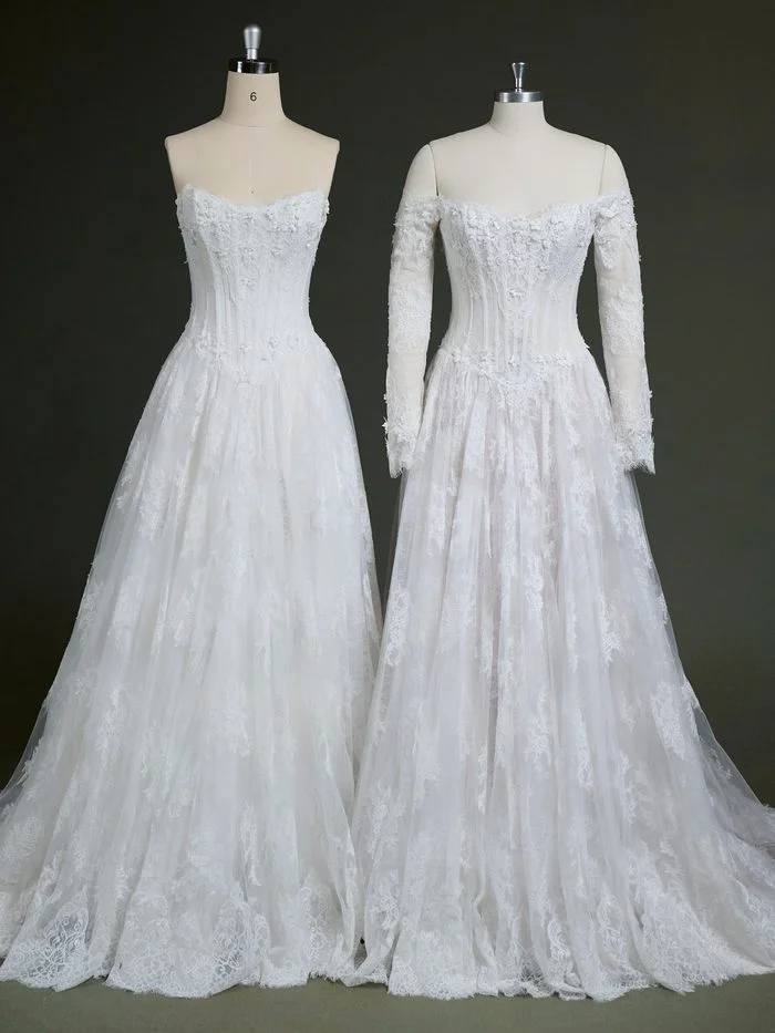 Two versions of the Kitaro by Maggie Sottero wedding gown are displayed side by side on dress forms. Both feature a romantic lace ballgown silhouette with a corset-inspired bodice, floral lace appliqués, and a full tulle skirt. The gown on the left is shown strapless with a sweetheart neckline, while the gown on the right includes detachable off-the-shoulder long lace sleeves for added coverage and versatility.