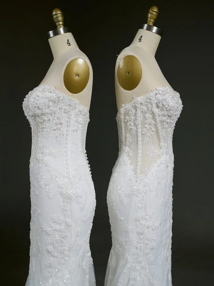 Side-profile comparison of two versions of the Benjie Royale by Maggie Sottero wedding gown displayed on dress forms. Both gowns feature a fitted silhouette with sparkling lace appliqués, beaded embellishments, and a sweetheart neckline. The gown on the left has a fully lined corset bodice that creates a more seamless, opaque look, while the gown on the right features a sheer bodice with visible boning and transparent side panels that emphasize the gown’s corset construction and lace detailing.