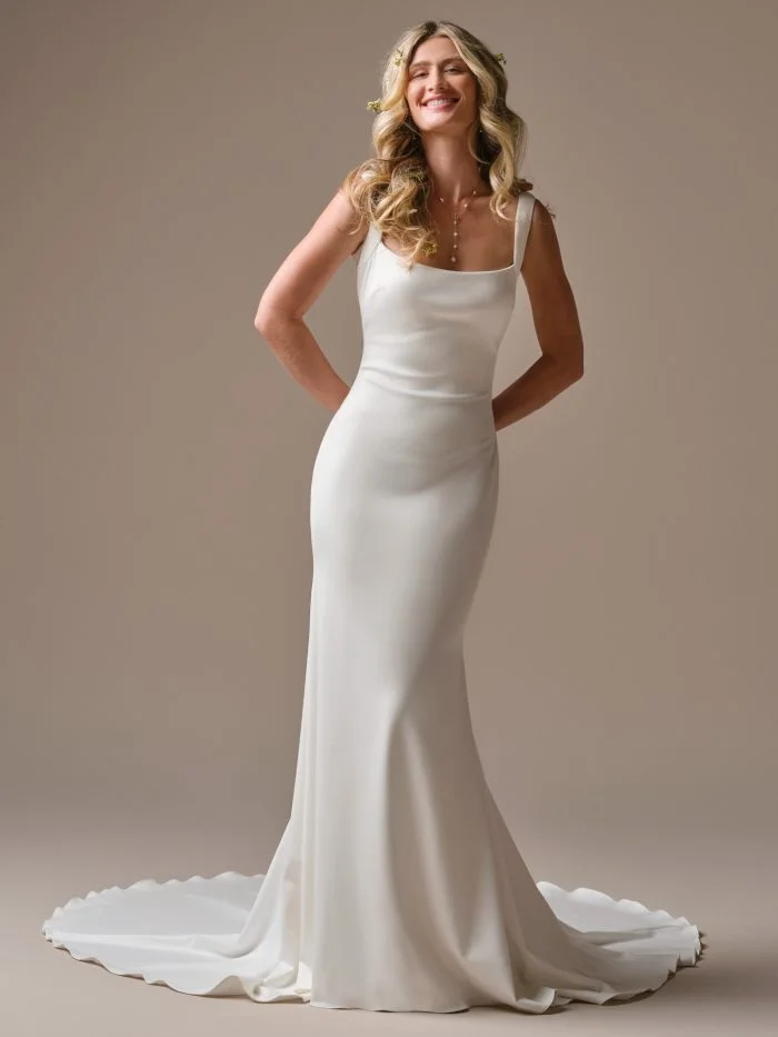 Front view of the Rebecca Ingram Lucille sheath wedding dress featuring a low draped back, delicate straps, and a sleek train.