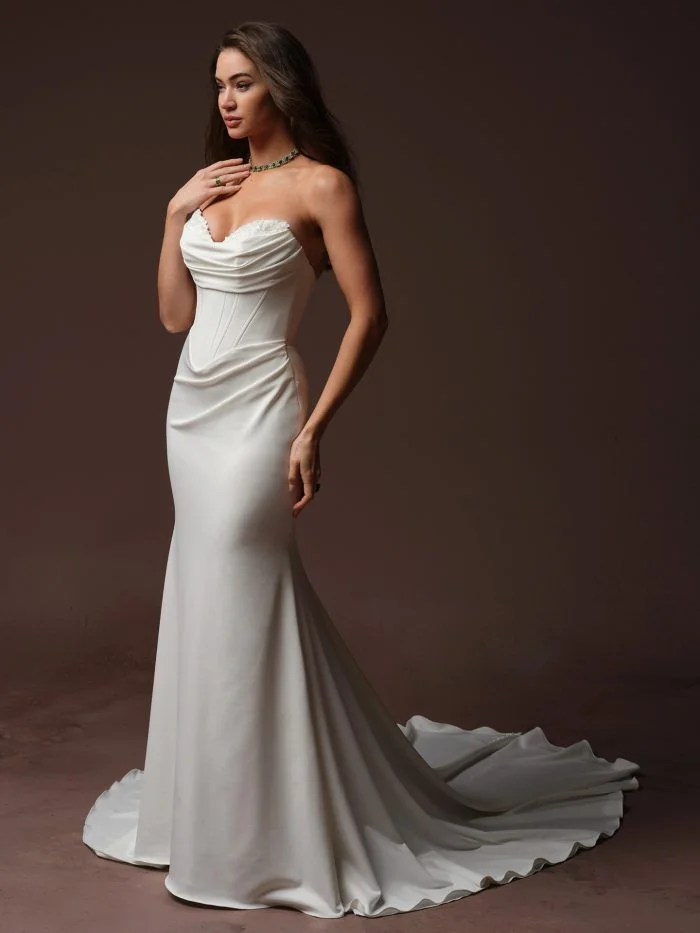 Front view of the Maggie Sottero Justina sheath wedding dress featuring a strapless draped neckline, structured corset bodice, lace trim, and fitted silhouette.