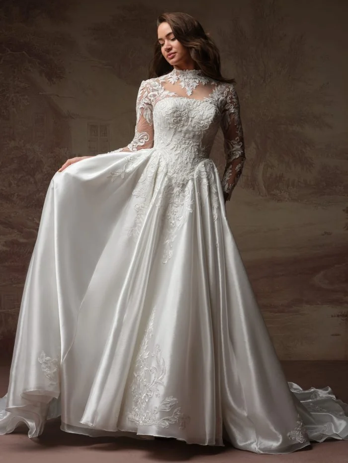 Maggie Sottero Dahlia ballgown wedding dress featuring a straight neckline, dramatic basque waist, embellished floral lace, and detachable long lace sleeves.