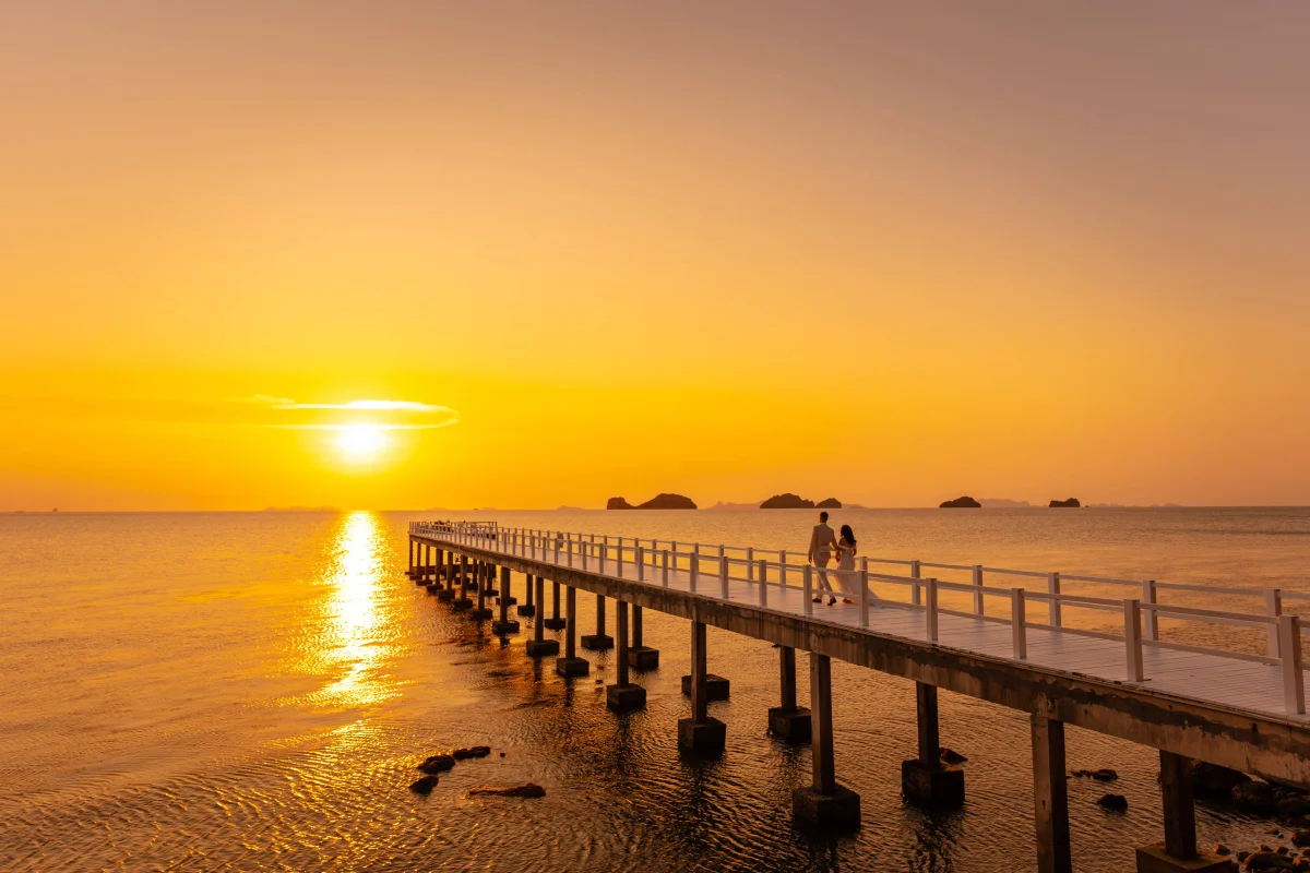 bride-and-groom-walking-on-a-dock-by-the-beach-during-sunset-at-conrad-koh-samui-thailand