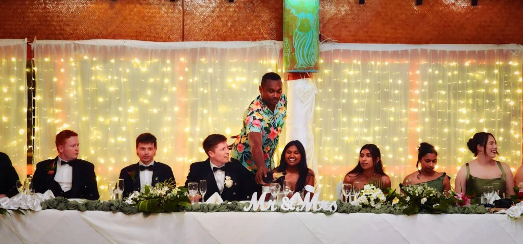 beach-wedding-of-mishka-and-hamish-at-the-rarotongan-beach-resort-cook-islands-bride-and-groom-with-guests-at-the-reception-table