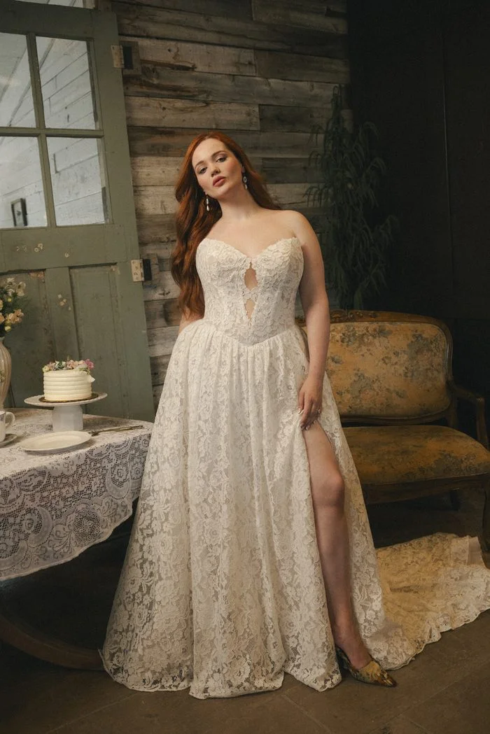 Narelle boho floral wedding dress featuring allover floral lace, a sweetheart neckline with illusion cutout detail, a flowing A-line skirt, and a dramatic thigh-high slit in a romantic vintage-inspired setting.
