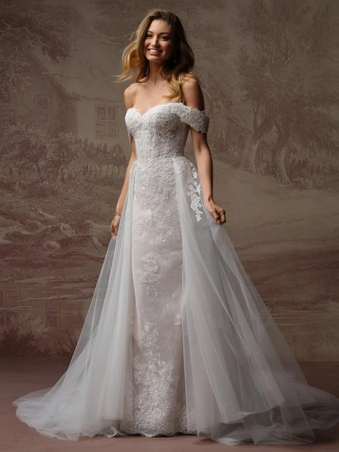Esmeralda Lane boho floral wedding dress with a detachable tulle overskirt train, featuring romantic floral lace appliqués, an off-the-shoulder neckline, and a versatile two-in-one bridal look.