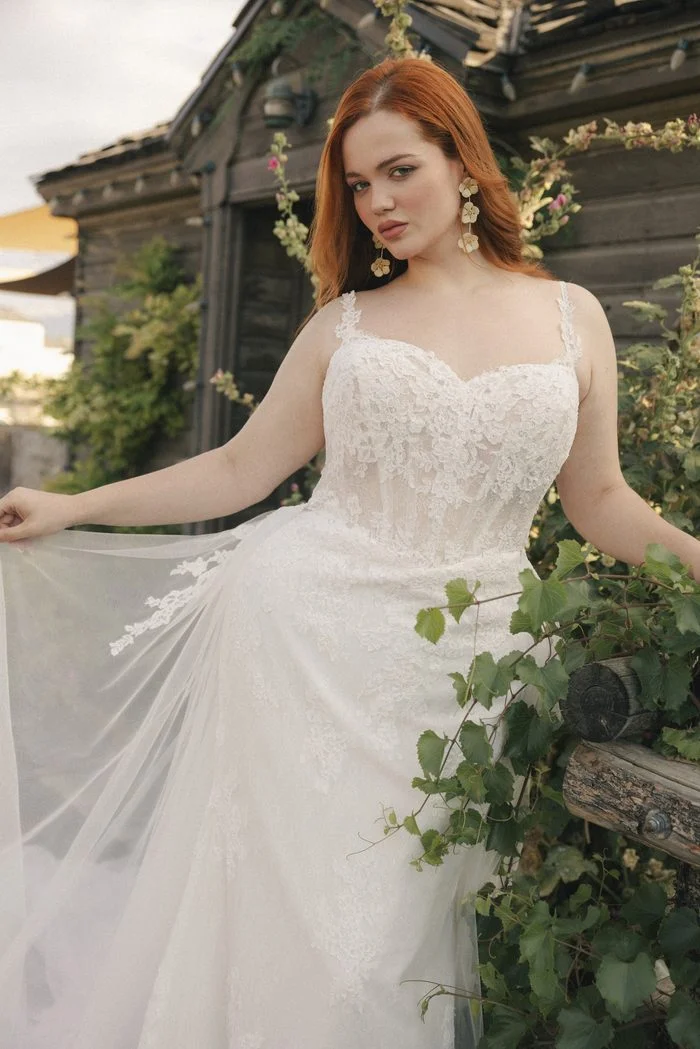 Esmeralda Lane boho floral wedding dress featuring 3D lace appliqués, delicate spaghetti straps, and a sheer corset bodice in a romantic outdoor setting.