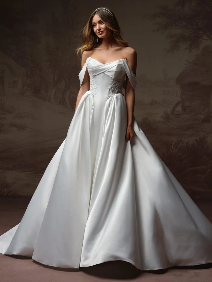 Gigi ballgown wedding dress with detachable cap sleeves, featuring a draped strapless neckline, lace-accented corset bodice, and a voluminous satin skirt for a romantic boho-inspired bridal look.