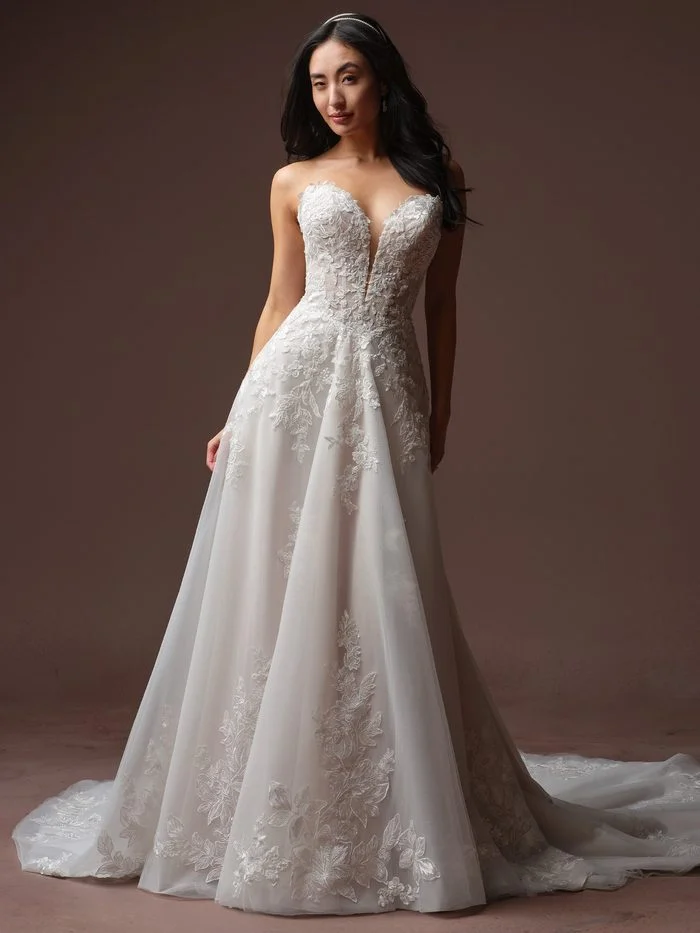 Bernadine boho floral A-line wedding dress with a plunging sweetheart neckline, dimensional floral lace appliqués, and a soft tulle skirt accented with embroidered botanical details and a sweeping train.