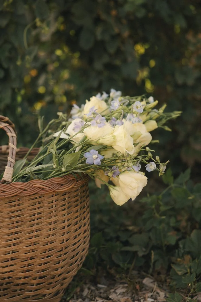 Basket of fresh garden flowers featuring ivory blooms and delicate lavender accents, styled as romantic floral inspiration for a boho wedding aesthetic.