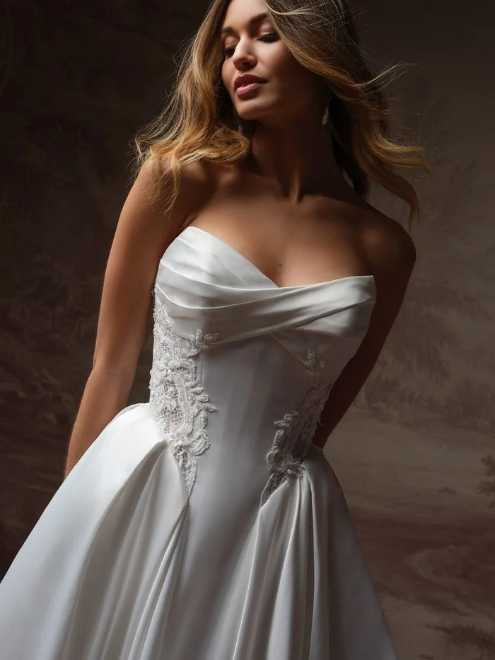 Close-up of the Gigi wedding dress featuring detachable panniers, a draped strapless neckline, lace-accented corset bodice, and voluminous satin side details for a dramatic ballgown silhouette.