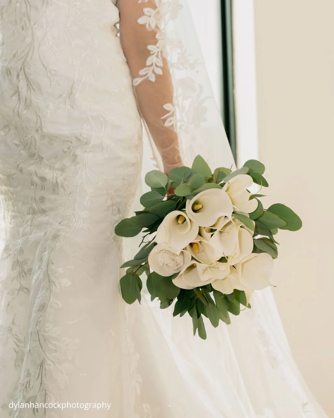 a bride holds her bouquet in a close up shot that highlights the elegance of her wedding attire and floral arrangement dylanhancockphotography