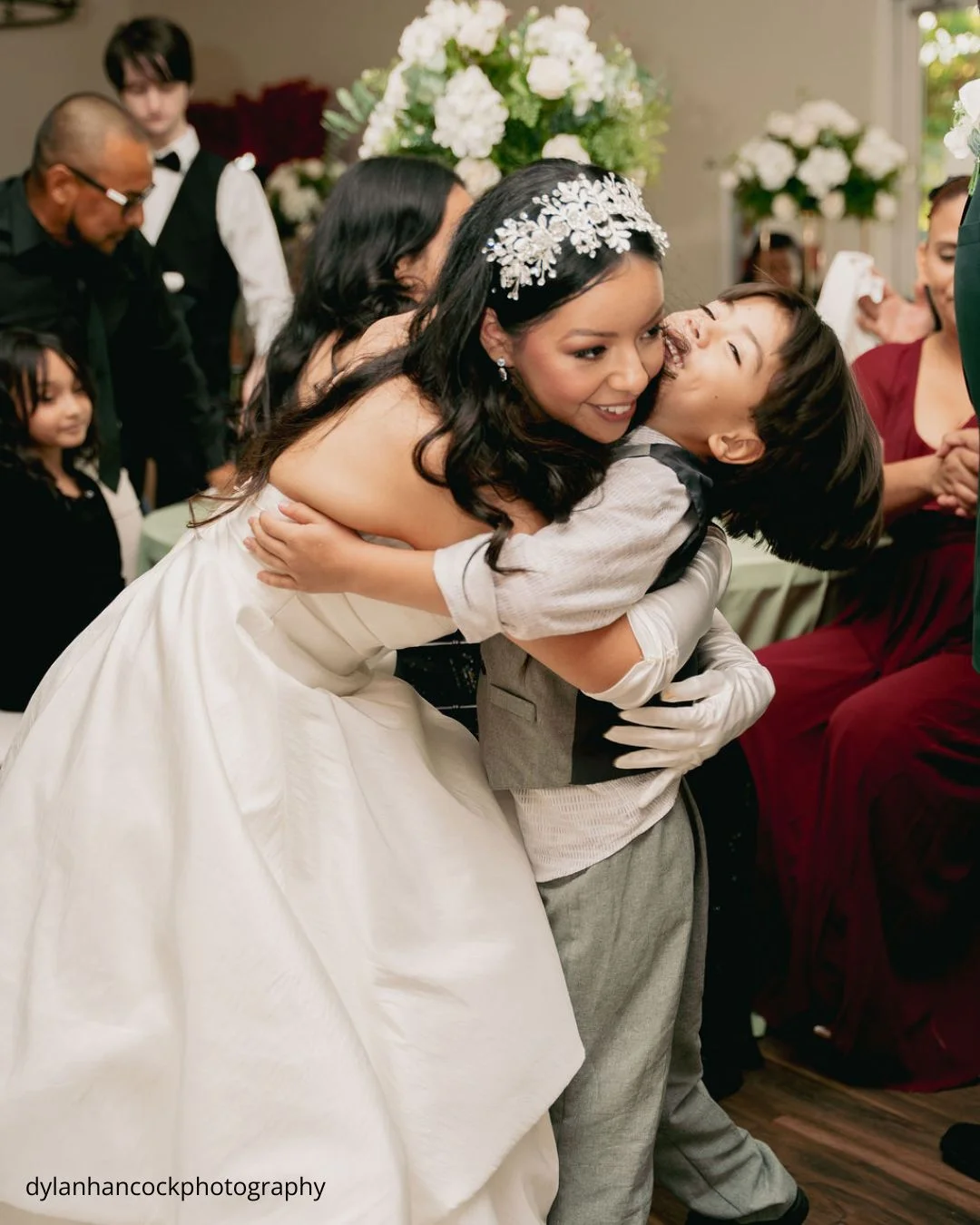 bride hugs young boy at wedding reception dylanhancockphotography