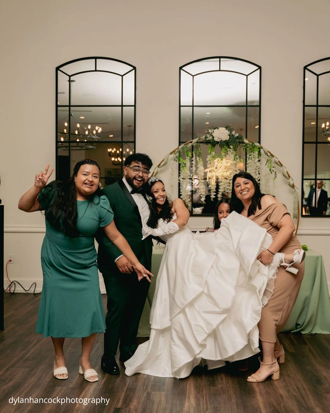 bride groom and guests posing under floral arch dylanhancockphotography