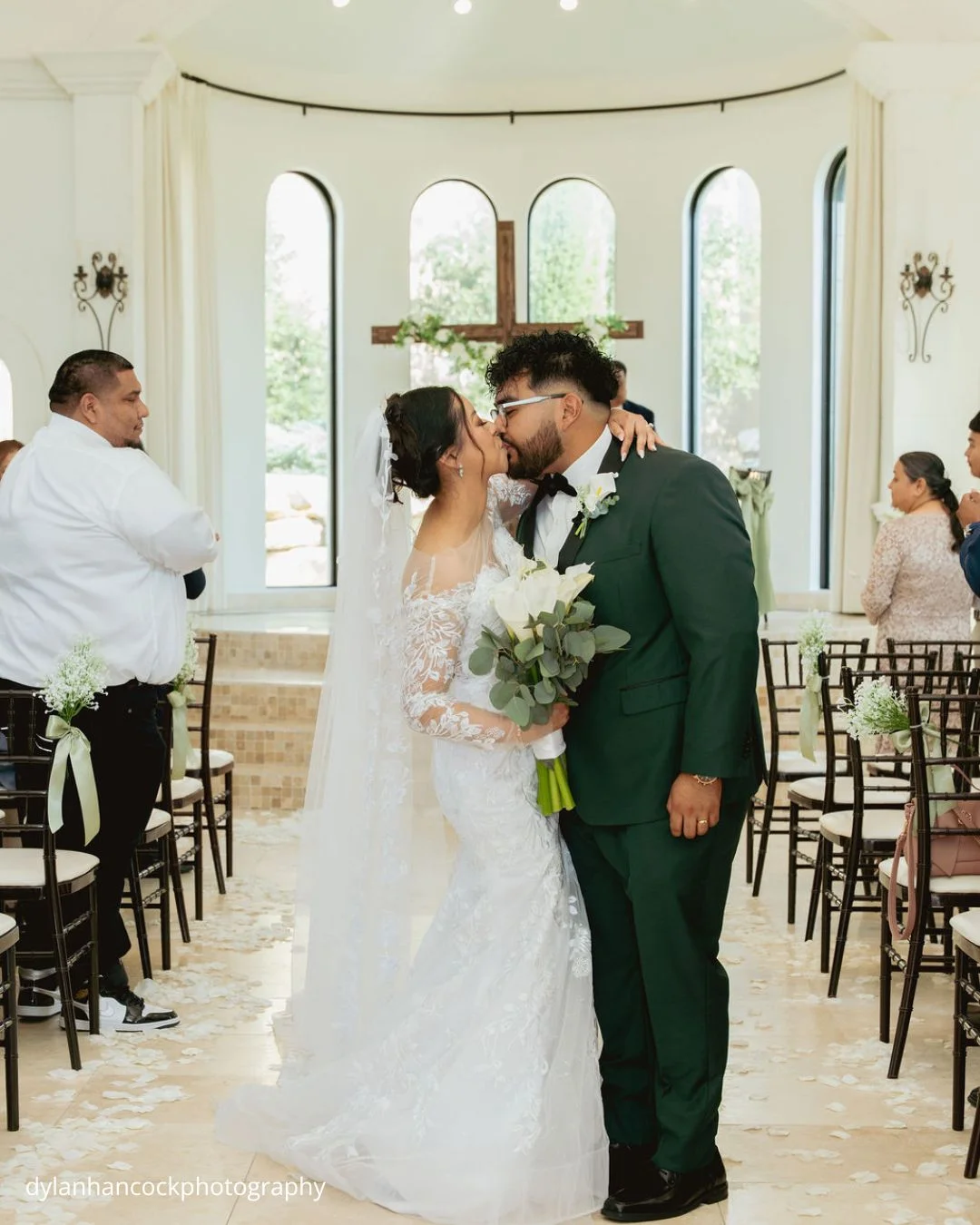 the bride and groom share a kiss during their wedding ceremony in a modern sunlit church dylanhancockphotography