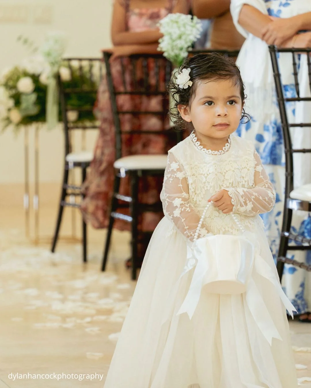 flower girl holding white bucket standing among rose petals dylanhancockphotography