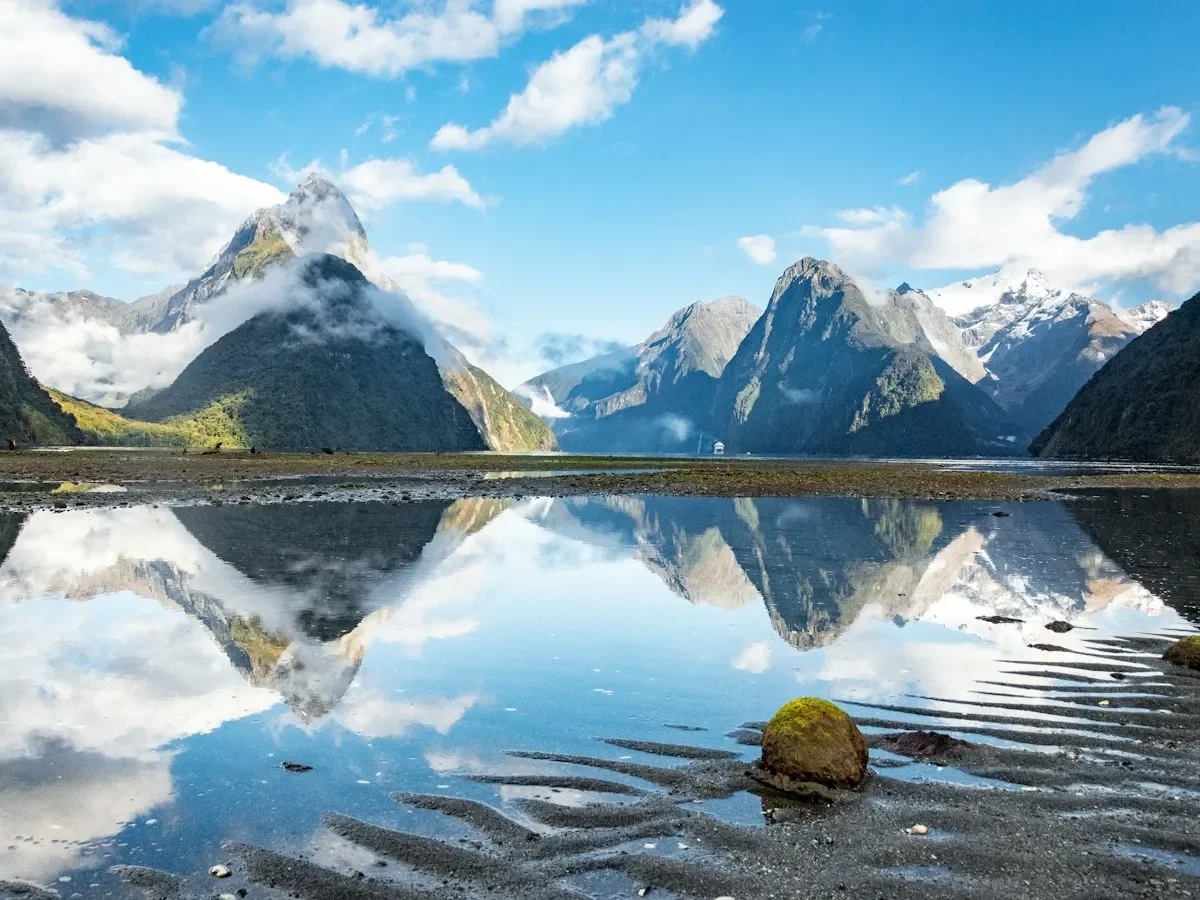 Mitre Peak and snowy mountains reflected in the still water of Milford Sound, New Zealand