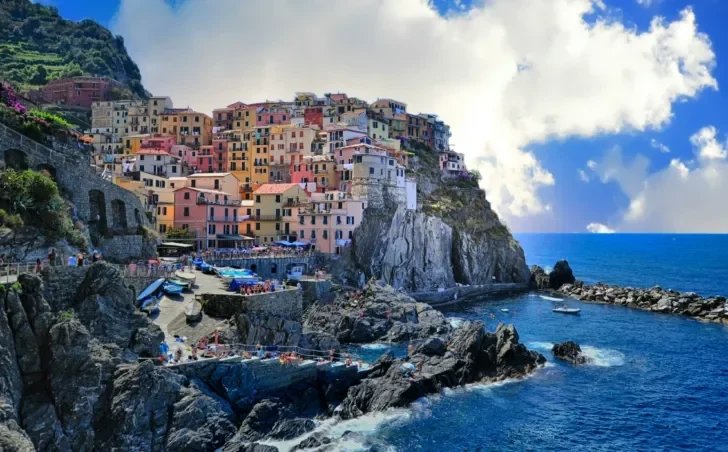 A stunning coastal view of Manarola, one of the five villages of Cinque Terre, Italy. The colorful buildings are stacked on the rocky cliffs overlooking the deep blue Ligurian Sea.