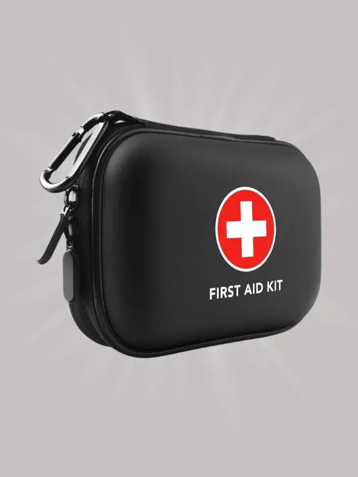 A compact black first aid kit with a hard shell case, featuring a red cross symbol and a carabiner clip for easy portability.