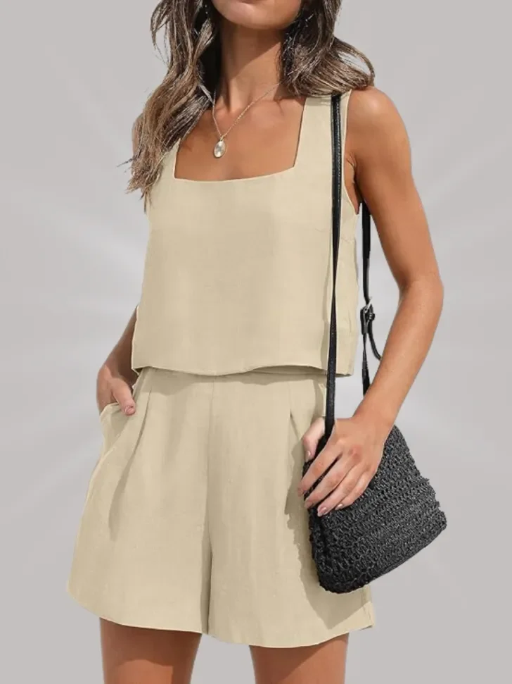 Beige two-piece outfit with a square neckline and pleated shorts, paired with a black woven crossbody bag.